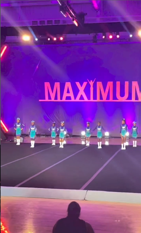 The full squad performing on a championship stage in front of a packed arena